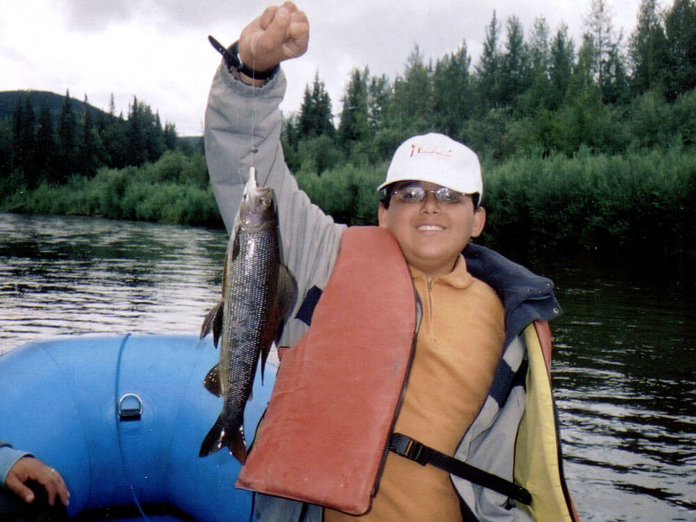 Catching Arctic Grayling. A young man holds up his prize catch - an Arctic Grayling.